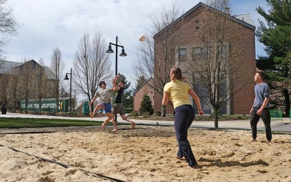 学生们在校园里打沙滩排球，背景是玛拉和邮箱